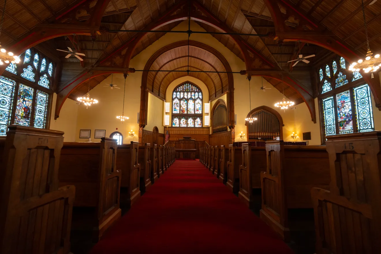 The red-carpeted center aisle of the sanctuary, lined with carved pews